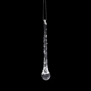 Clear glass icicle pendant close-up, delicate hanging decoration for Christmas tree and holiday display.
