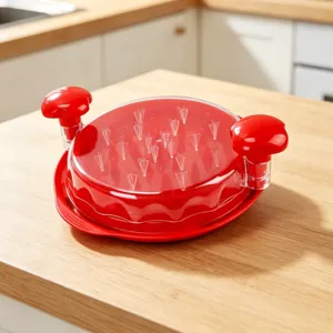 Primo piano dettagliato di un tritacarne manuale rosso con coperchio trasparente e punte.