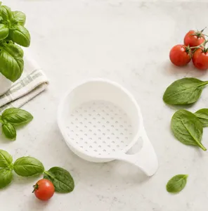 Detail view of white mini plastic draining basket for fruit washing and kitchen vegetable use.