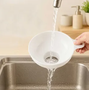 Detailed view of the wide-mouth white plastic kitchen funnel in use washing under clean water.