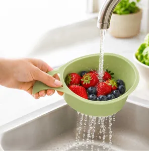 Mini plastic fruit rinse colander detail shot showing convenient handle and drainage holes in sink.