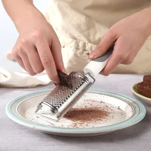 Vista ravvicinata della grattugia da cucina in acciaio inox che grattugia il cioccolato.