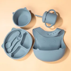 Silicone baby feeding set with divided plate, bowl, sippy cup, spoon, fork, and cute bib.