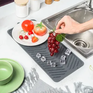 Detailed view of the gray silicone drying mat showing its textured drainage grooves and kitchen use.