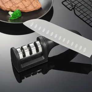 Kitchen knife sharpener detail showing multi-slot sharpening tool on dark reflective surface.