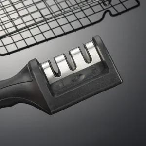 Close-up of a black handheld kitchen knife sharpener with three grinding slots and numbered design.