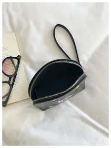 Detailansicht der schwarzen bestickten Handgelenktasche mit Blumenmuster und Reißverschluss.