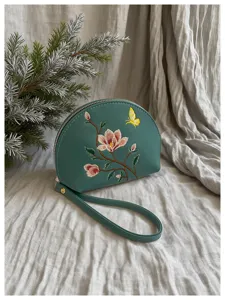 Dunkelgrüne halbrunde Handgelenktasche mit eleganter Blumenstickerei und feinem Schmetterling.