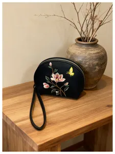 Detailansicht der schwarzen bestickten Geldbörse mit Blumenmuster und praktischer Handschlaufe.