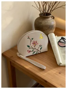 Elegante weiße Kosmetiktasche mit Blumenstickerei und Handschlaufe, stilvolles Etui.