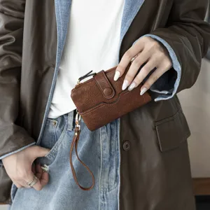 Portefeuille femme marron compact à deux volets avec fentes pour cartes et dragonne.