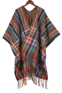 Close-up detail of colorful bohemian knitted poncho cape with fringe and warm plaid pattern.