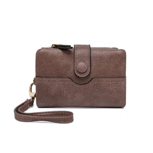 Détail de petit portefeuille marron, porte-carte pliable compact avec dragonne et fermoir bouton.