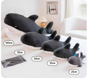 Detailed view of cute plush killer whale shark soft toys arranged by size on a cozy bed.