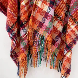 Colorful bohemian knitted poncho with geometric pattern and tassels for autumn winter.
