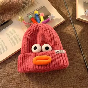 Süße rosa Strickmütze mit lustigen Cartoon-Augen und Lippen für die kalte Wintersaison.