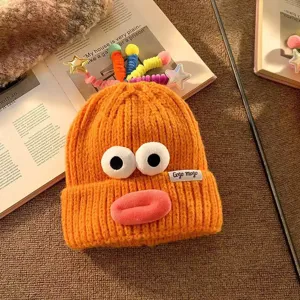 Niedliche lustige Strickmütze mit großen Augen und dicken Lippen, modisches warmes Winteraccessoire.