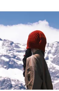 Red knit beanie detail, hollow wool cap texture, autumn winter outdoor travel style.