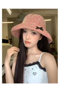 Primo piano dettagliato del cappello da pescatore a quadretti rossi con un fiocco nero.