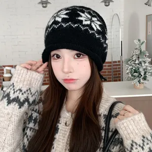 Close-up detail of cozy black and white knit beanie with Nordic pattern and rolled cuff.