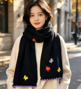 Close-up detail of the cozy black knitted winter scarf featuring colorful butterfly embroidery.