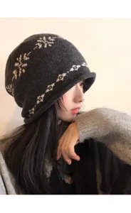 Gros plan d'un bonnet slouchy en tricot gris foncé doté d'un motif flocon vintage norvégien.