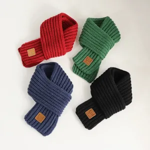 Detailed view of children colorful knit winter scarf with leather label detail and warm texture.