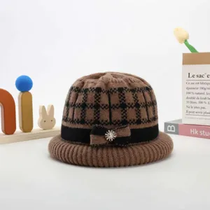 Knit hat detail showing warm wool texture, plaid pattern, and rhinestone bow ornament.