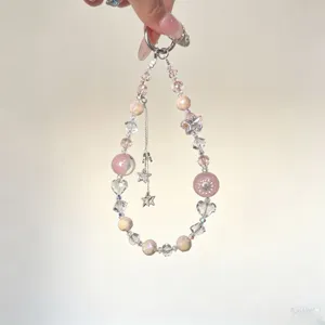 Detail shot of a sparkling crystal beaded phone charm with cute star tassels and pink beads.