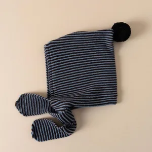 Children winter knit beanie hat with blue brown stripes and cute pom pom detail close up.