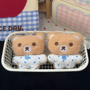 Portachiavi in peluche di orsetto marrone in dettaglio, con abiti a pois blu e catenella in metallo.