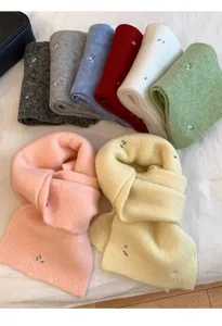 Detailed view of colorful knitted scarves with delicate floral embroidery, soft winter texture.