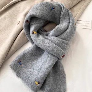 Grey knitted winter scarf with cute dachshund embroidery, soft texture and detail view.