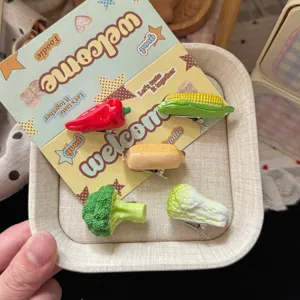 Close-up detail of cute 3D vegetable hair clips featuring corn, broccoli and chili designs.