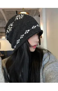 Vue détaillée d'un bonnet en tricot Fair Isle gris foncé avec un motif de flocon de neige.