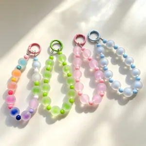 Dettaglio charm per cellulare con perline colorate, cinturino in acrilico, portachiavi estetico.