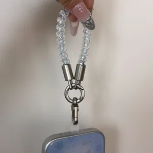 Close-up of blue beaded phone lanyard with metal clasp and clear tether tab for daily anti-loss.