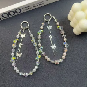 Detail shot of luxury crystal pearl phone charm with cute butterfly pendant and beaded strap.