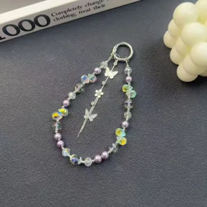 Close-up detail of crystal phone charm with butterflies and purple pearls, exquisite decor.
