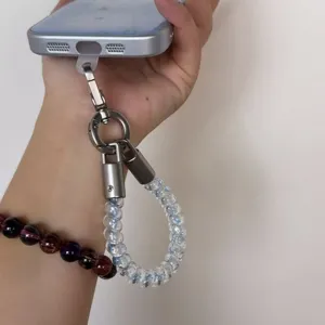 Short coiled bead phone charm strap, transparent phone lanyard wristlet detail and clasp close up.