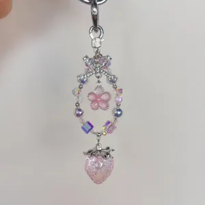 Detailed close-up of a sparkling crystal strawberry and pink flower beaded keychain charm.