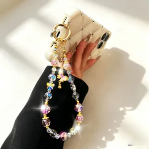 Detailed shot of sparkling crystal and gold butterfly phone charm strap, elegant accessory.