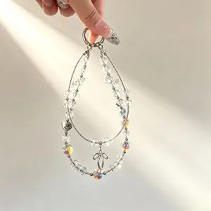Doppelte Kristall Handykette mit schimmernden Perlen und Schleifen Anhänger Detailansicht.