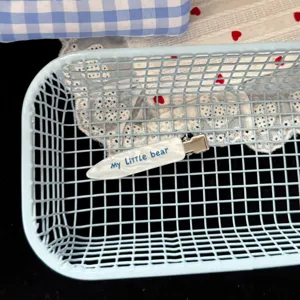 Gros plan détaillé de la jolie pince à cheveux blanche avec lettrage dans un panier.
