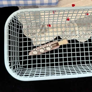 Joli pince à cheveux rose à carreaux avec motif patte, gros plan dans un panier.