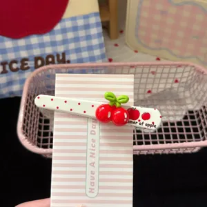 Close-up detail of cute sweet cherry hair clip with red dots and pink display card.