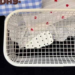 Close-up van een stijlvolle zwart-witte geplooide polkadot haarspeld in een witte mand.