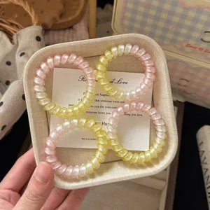 Dettaglio in primo piano di elastici per capelli a spirale rosa e gialli, stile estetico dolce.