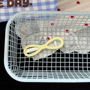 Detail shot of a cute yellow polka dot hair clip inside a blue mesh basket with lace fabric.