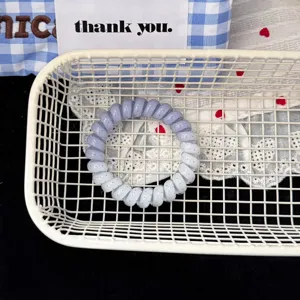 Close-up detail of the gradient blue telephone wire hair tie displayed in a white basket.